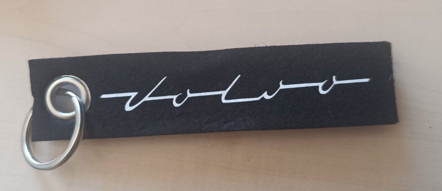 Schlüsselanhänger mit dem Schriftzug "volvo" in weiß auf schwarzem Hintergrund.