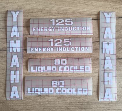 Aufkleber mit den Beschriftungen "YAMAHA", "125 ENERGY INDUCTION" und "80 LIQUID COOLED".