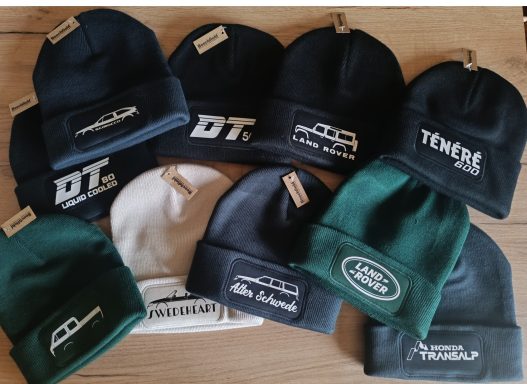 Zehn verschiedene Mützen in grünen, weißen und blauen Farbtönen mit Logos.