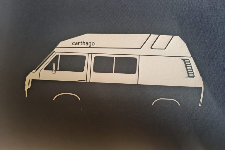 Silhouette eines Campingbusses in Schwarz und Weiß auf dunklem Hintergrund.