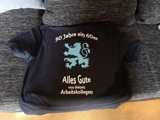 Schwarzes T-Shirt mit blauem Druck: "50 Jahre ein Löwe - Alles Gute von deinen Arbeitskollegen."