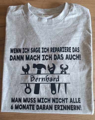 Graues T-Shirt mit Werkzeugmotiven und dem Text: "Wenn ich sage ich repariere das, dann mach ich das auch!"