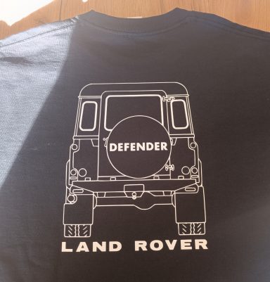 Schwarzes T-Shirt mit weißem Druck eines Land Rover Defender im Rückansicht.
