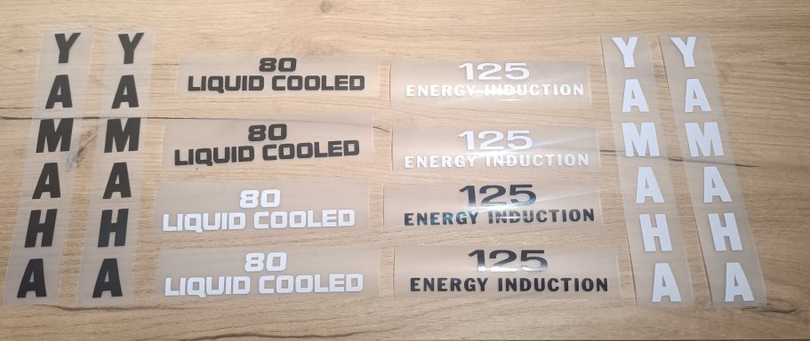 Aufkleber mit "Yamaha" und "Liquid Cooled" in verschiedenen Schriftgrößen.